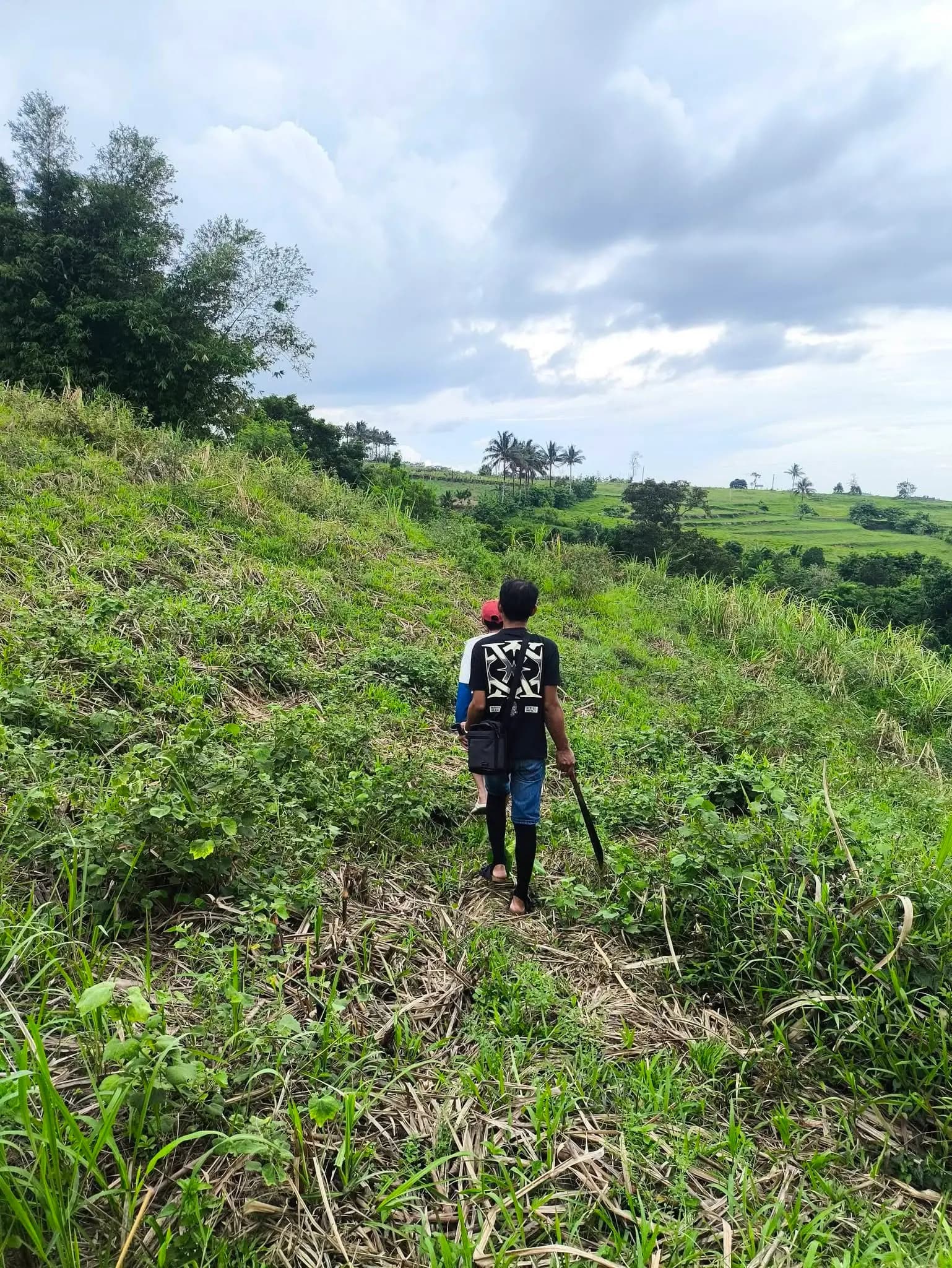 Leonor Surveying Services field crew traversing a hillside with survey equipment in Silay, Negros Occidental