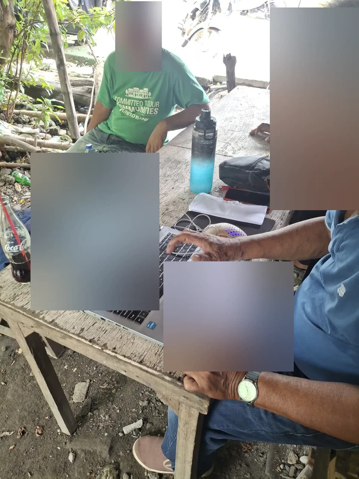 Surveyor comparing a printed document with laptop records while another person sits across the table