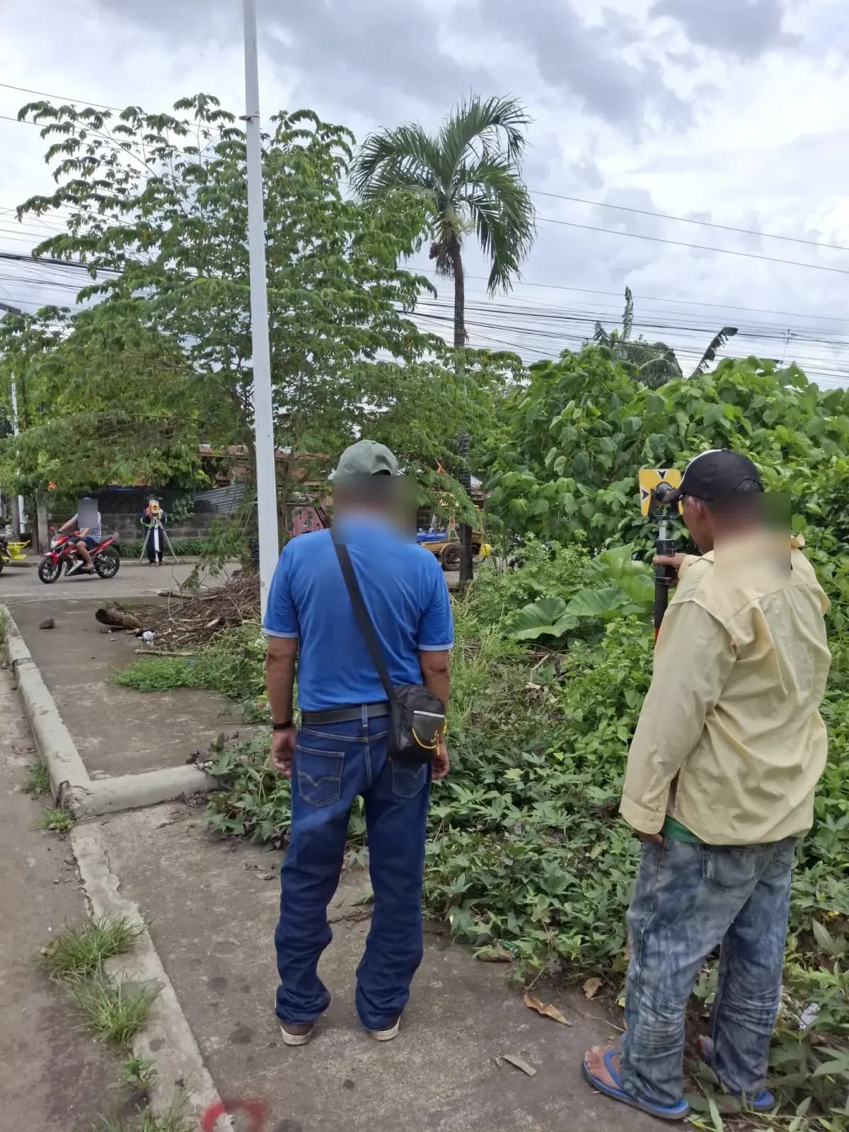 Field crew facing a total station across a neighborhood street from a roadside prism position