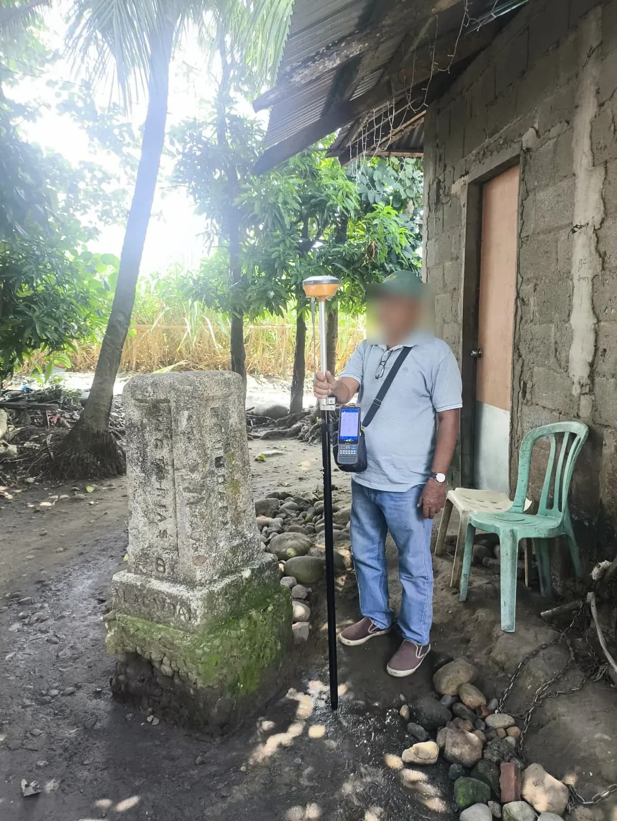 A person holding a GNSS receiver and controller beside a concrete monument in E. B. Magalona